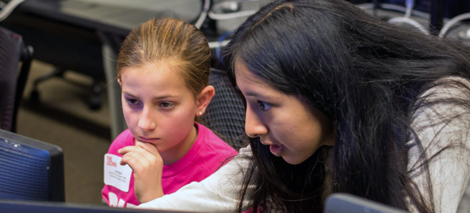 An iSchool student teaches a Girl Scout at the iSchool's 