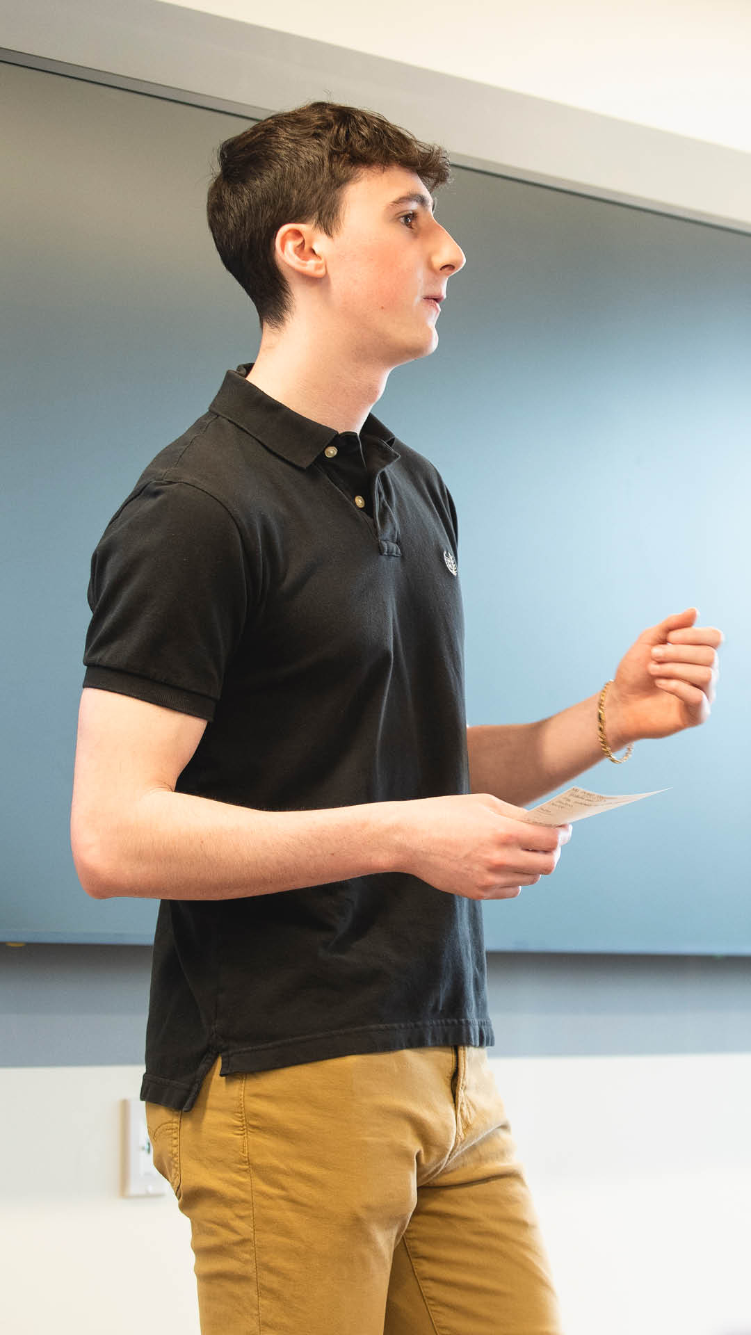 Boy presenting in class with notecard in his hand