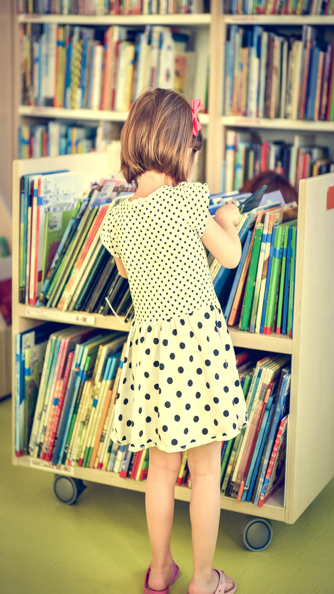 young girl looking through library books