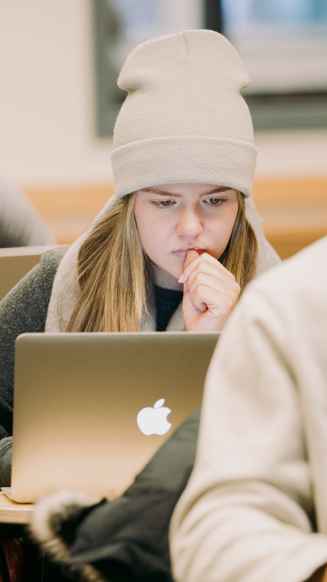 Girl in a hat staring at computer in class